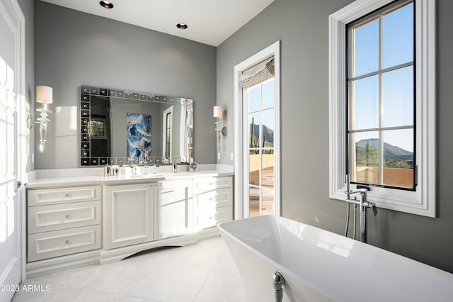 bathroom featuring tile patterned flooring, vanity, a mountain view, and a tub to relax in