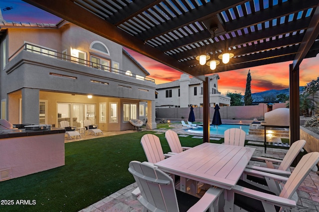 patio terrace at dusk featuring a fenced in pool, a yard, a balcony, a fenced backyard, and outdoor dining space