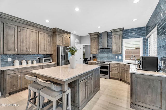 kitchen featuring a sink, a kitchen island, stainless steel appliances, wall chimney exhaust hood, and a toaster