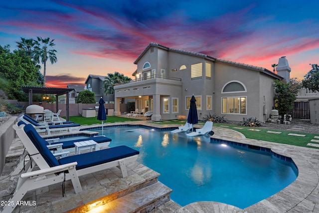 pool at dusk featuring a fenced in pool, a lawn, a fenced backyard, a pergola, and a patio