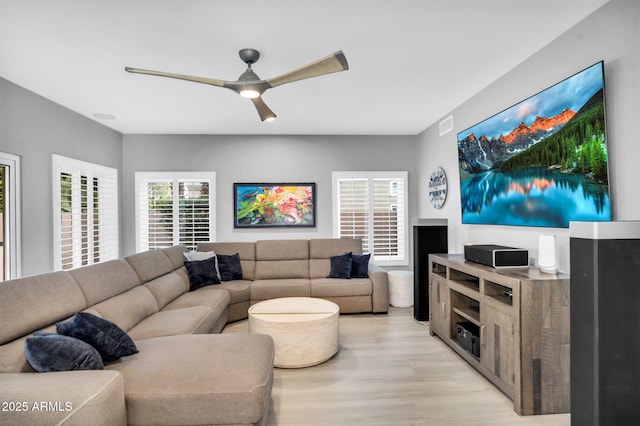 living room featuring light wood finished floors, visible vents, and ceiling fan