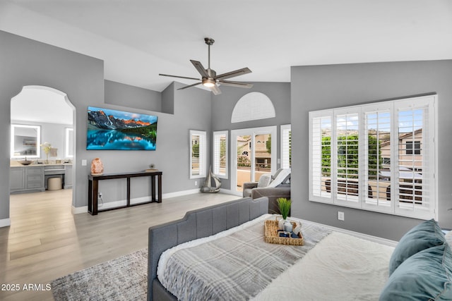 living area with high vaulted ceiling, baseboards, ceiling fan, and wood finished floors