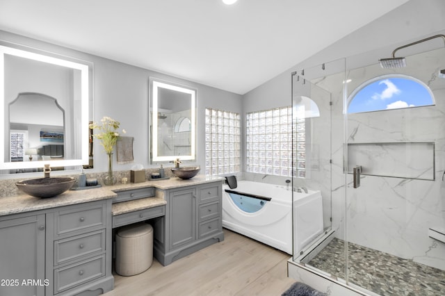 bathroom with a sink, a marble finish shower, double vanity, and vaulted ceiling