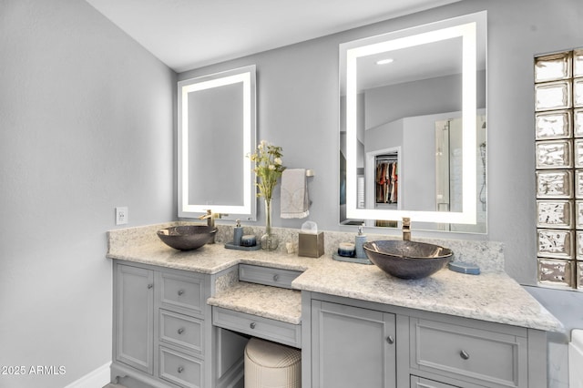 bathroom with double vanity, baseboards, and a sink