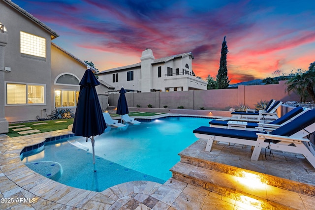 pool at dusk featuring a patio area, a fenced in pool, and a fenced backyard