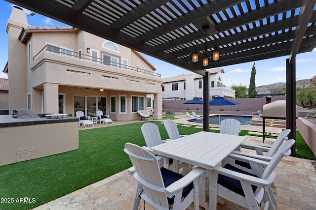 view of patio featuring exterior kitchen, outdoor dining area, fence, and a pergola