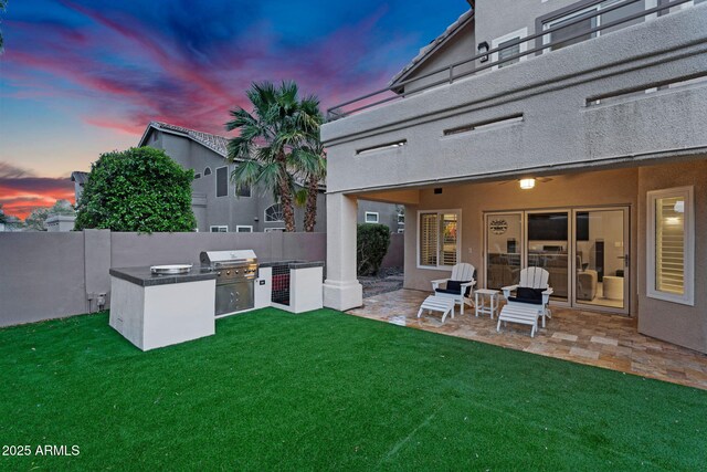 yard at dusk featuring exterior kitchen, a patio, and fence