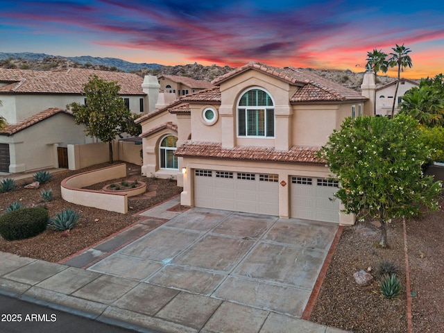 mediterranean / spanish house featuring stucco siding, a tiled roof, driveway, and a garage