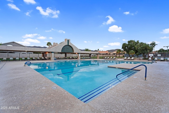 community pool with a patio and fence