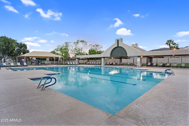 community pool with a patio area and fence