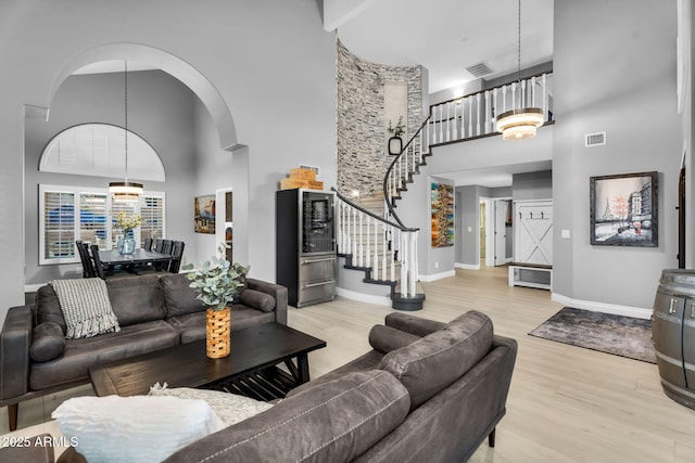 living area with stairs, wood finished floors, visible vents, and a chandelier