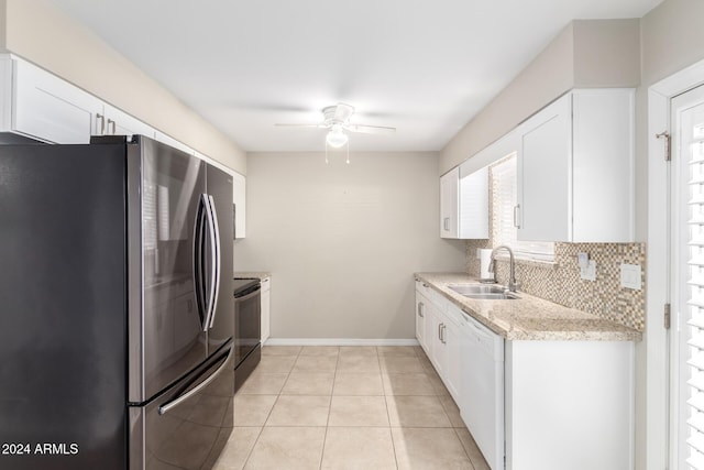 kitchen featuring white dishwasher, sink, light tile patterned floors, white cabinetry, and stainless steel refrigerator