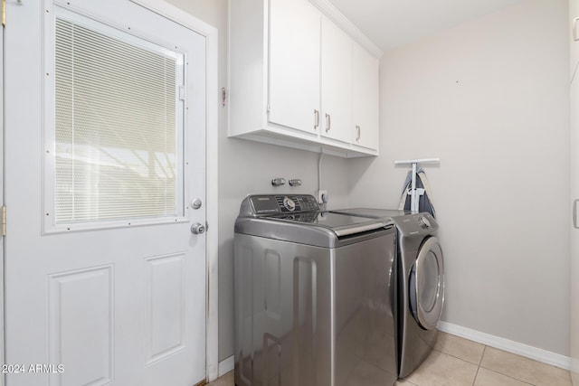 clothes washing area featuring washer and clothes dryer, cabinets, and light tile patterned floors