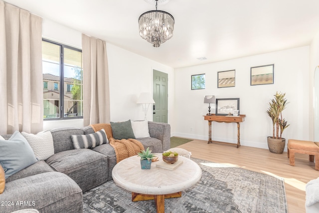 living room featuring a notable chandelier, plenty of natural light, and light wood-type flooring