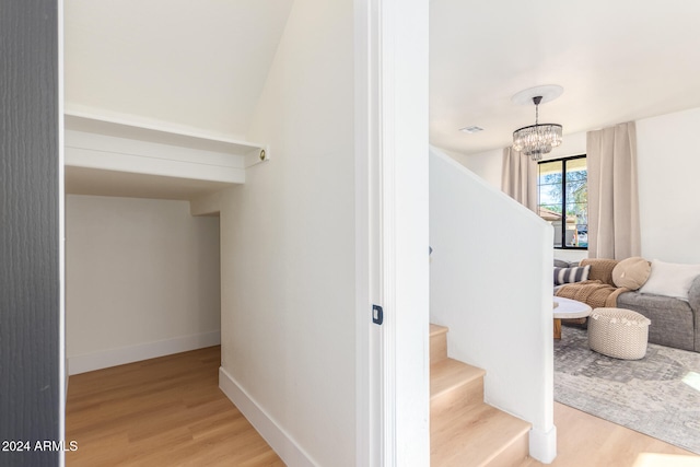 staircase featuring wood-type flooring and a notable chandelier