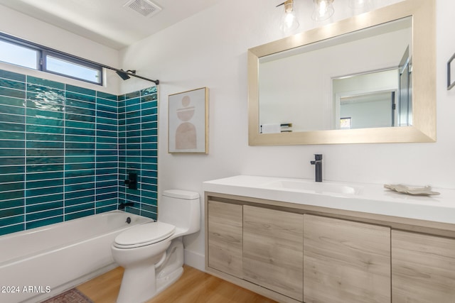 full bathroom with tiled shower / bath, wood-type flooring, vanity, and toilet