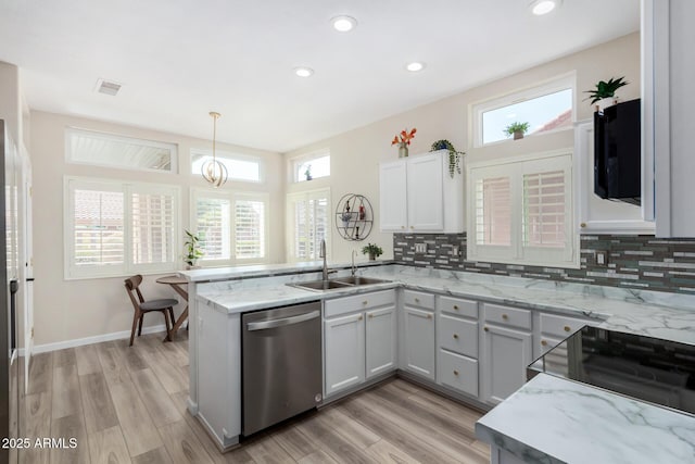 kitchen featuring kitchen peninsula, stainless steel dishwasher, pendant lighting, sink, and decorative backsplash