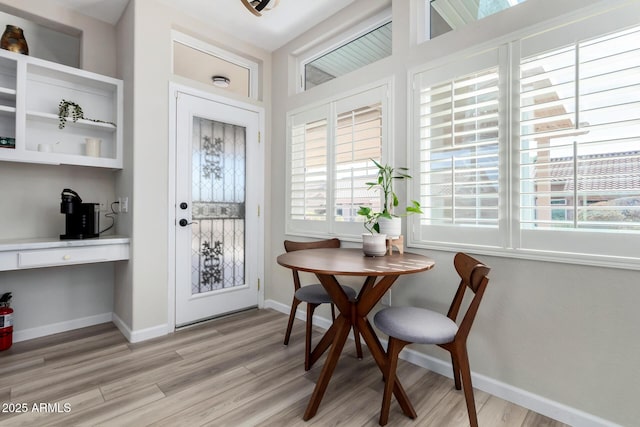 dining room with built in desk and light wood-type flooring