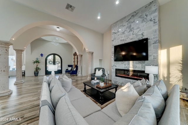 living room featuring decorative columns, vaulted ceiling, a fireplace, and light hardwood / wood-style floors