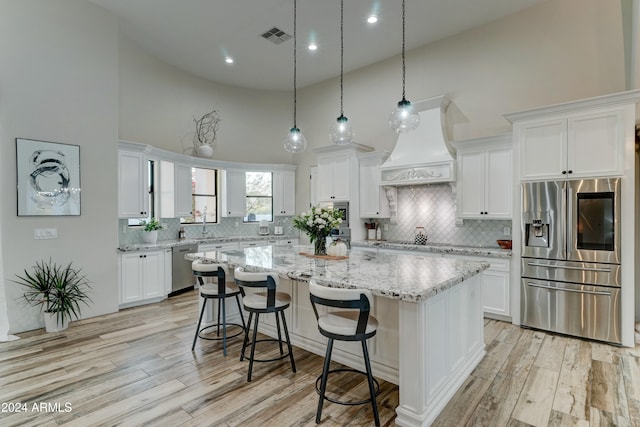 kitchen featuring a spacious island, light hardwood / wood-style flooring, white cabinetry, and stainless steel appliances