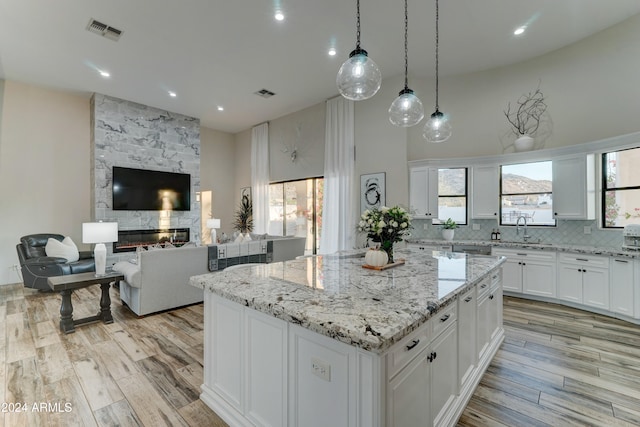 kitchen featuring light hardwood / wood-style floors, white cabinets, a fireplace, and a kitchen island