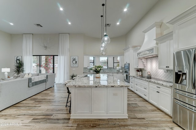 kitchen with a wealth of natural light, a kitchen island, white cabinetry, and stainless steel appliances