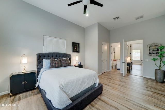 bedroom featuring a high ceiling, ensuite bathroom, light wood-type flooring, and ceiling fan