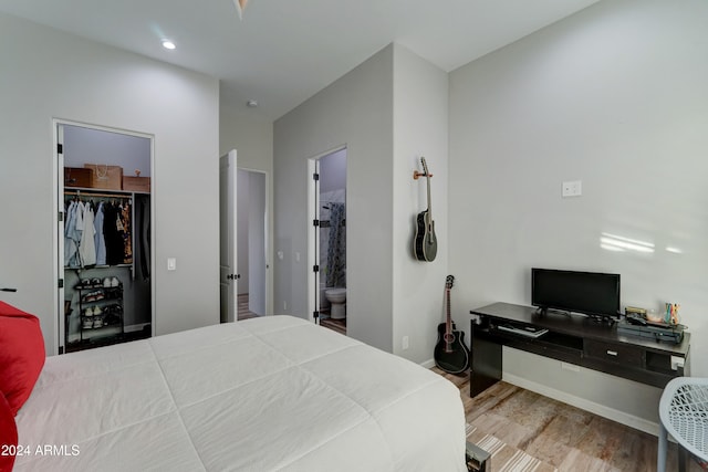 bedroom with a spacious closet, a closet, hardwood / wood-style floors, and ensuite bathroom