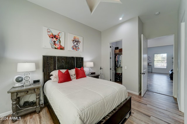 bedroom with a closet, light hardwood / wood-style flooring, and a walk in closet