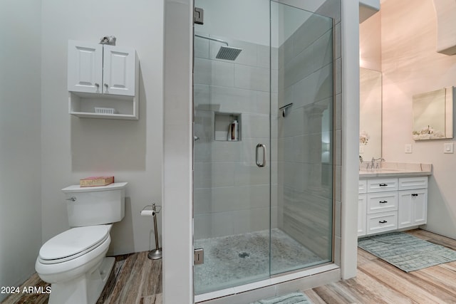 bathroom with toilet, an enclosed shower, hardwood / wood-style floors, and vanity