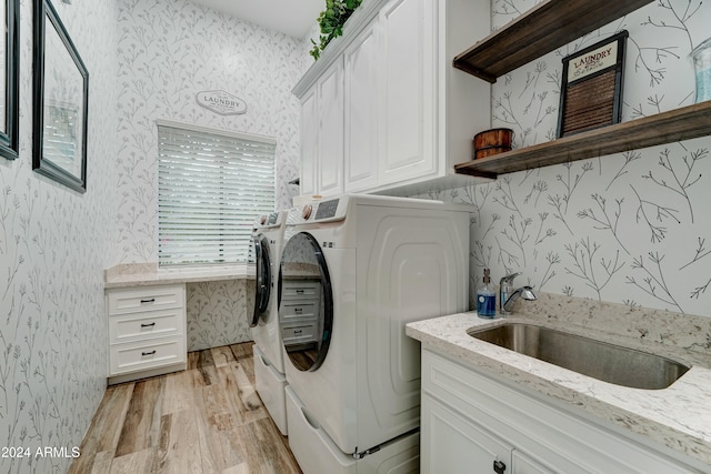 washroom featuring light hardwood / wood-style floors, sink, cabinets, and washer and clothes dryer