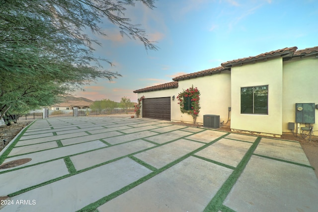 property exterior at dusk featuring cooling unit and a garage