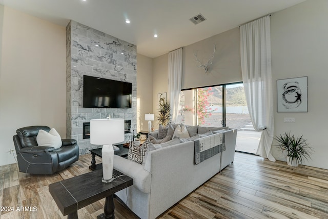 living room with light hardwood / wood-style flooring and a stone fireplace