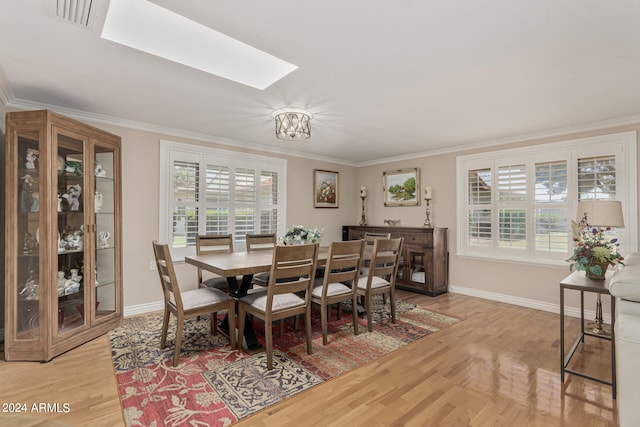 dining space featuring ornamental molding, a skylight, and light hardwood / wood-style floors