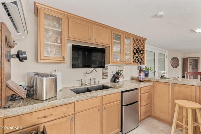 kitchen featuring fridge, light stone counters, sink, light tile floors, and stainless steel dishwasher