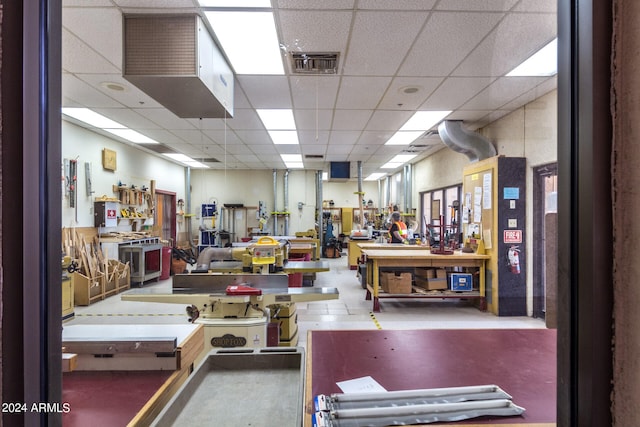 miscellaneous room featuring concrete flooring, a paneled ceiling, and a workshop area