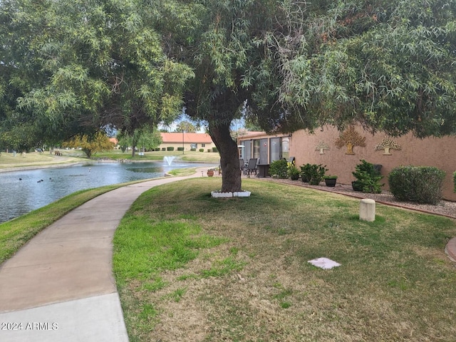 surrounding community with a water view and a yard