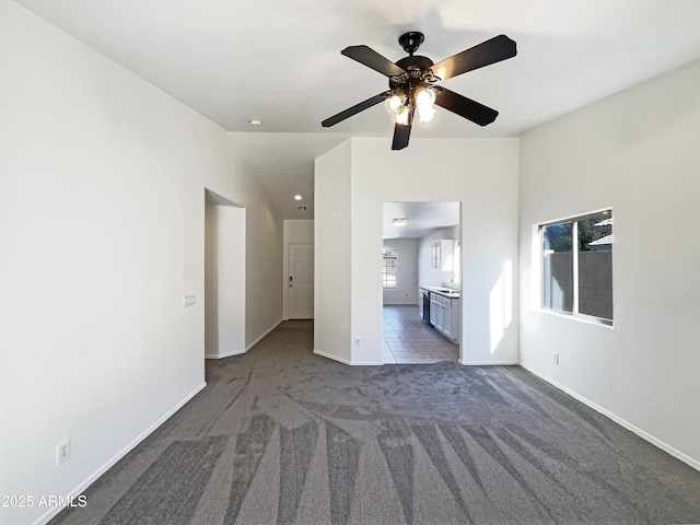 unfurnished living room with dark colored carpet and ceiling fan