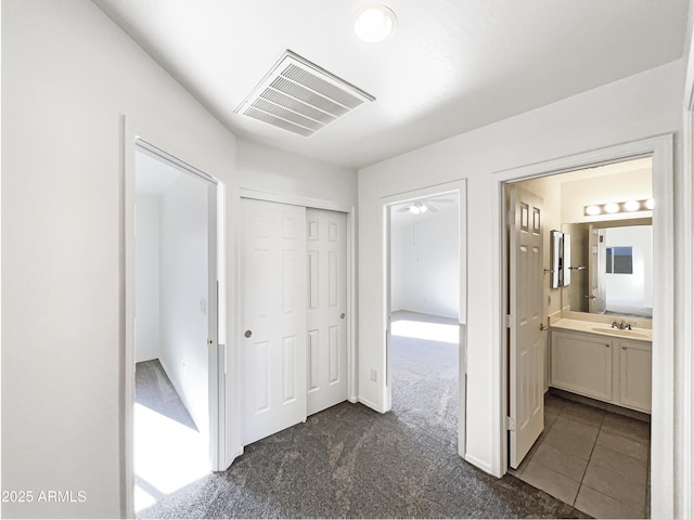 corridor with dark colored carpet and sink