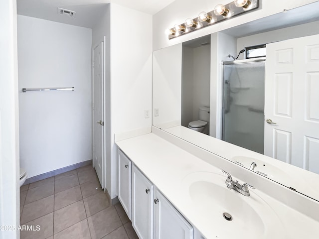 bathroom with tile patterned flooring, vanity, toilet, and a shower with shower door