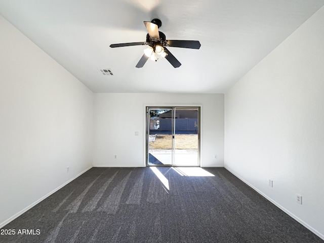 spare room featuring dark colored carpet and ceiling fan