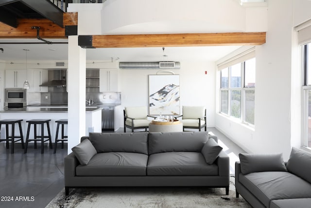 living room featuring beamed ceiling, sink, and concrete floors