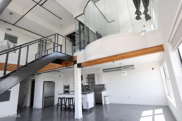 staircase with a towering ceiling and concrete flooring