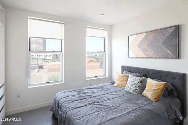 bedroom with multiple windows and concrete floors