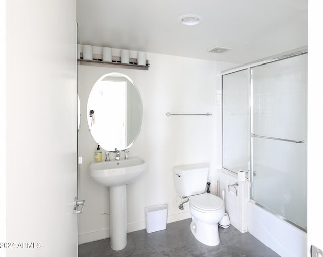 bathroom with enclosed tub / shower combo, toilet, and concrete floors