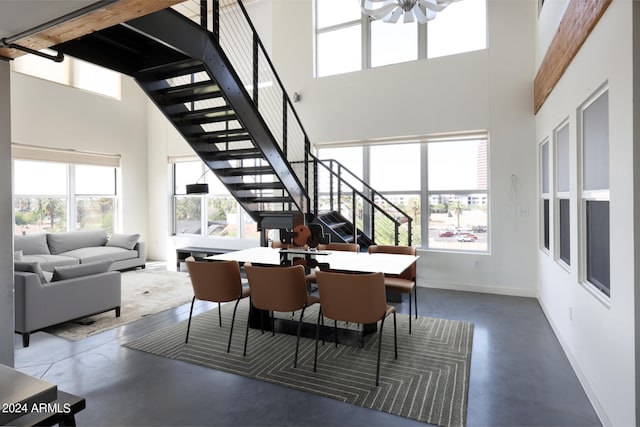 dining space featuring a towering ceiling, ceiling fan, and plenty of natural light