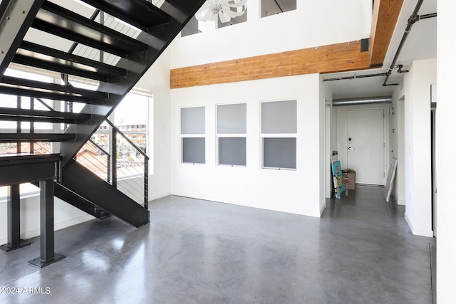 interior space with a high ceiling, ceiling fan, and concrete flooring