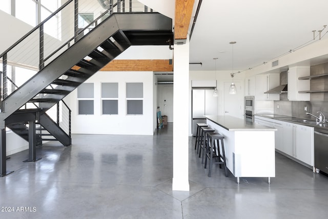 kitchen with white cabinets, hanging light fixtures, sink, a kitchen island, and a breakfast bar