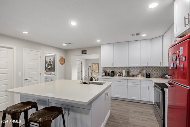 5702 S Beck Ave, Tempe, AZ 85283 - kitchen with a breakfast bar, a sink, stainless steel range with electric stovetop, freestanding refrigerator, and visible vents