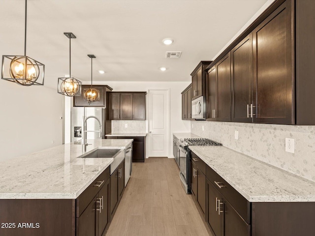 kitchen featuring hanging light fixtures, a large island, backsplash, appliances with stainless steel finishes, and sink